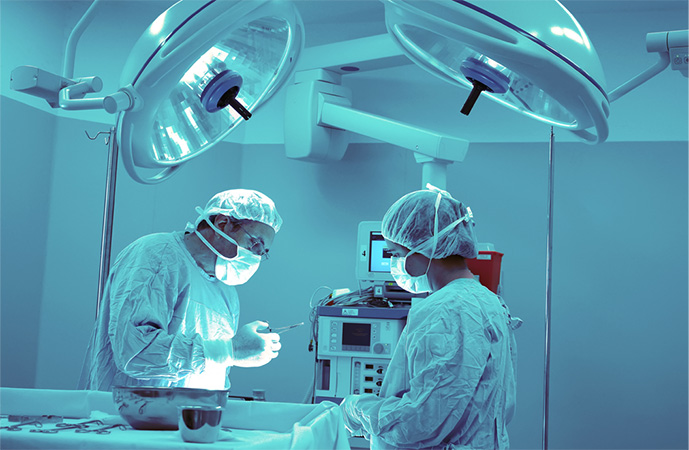 Cirujanos trabajando en un quirófano con iluminación y equipo especializado.
