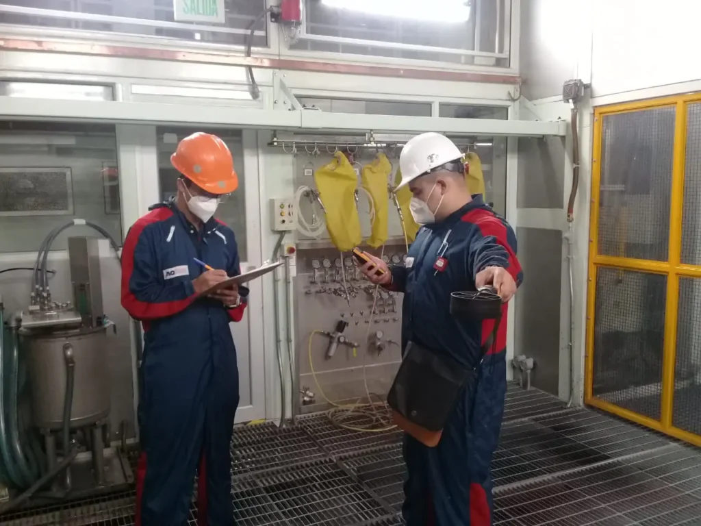 Técnicos especializados de AQM realizando medición de calidad del aire en un entorno industrial con equipo especial para optimizar sistemas de filtración HVAC.