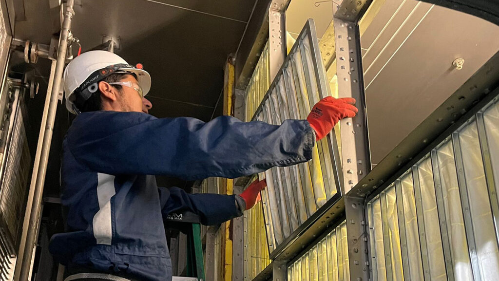 Técnico de AQM especializado instalando sistemas de filtración de aire industrial en un entorno controlado. Garantizar la calidad del aire y una filtración eficiente es clave en los procesos industriales modernos