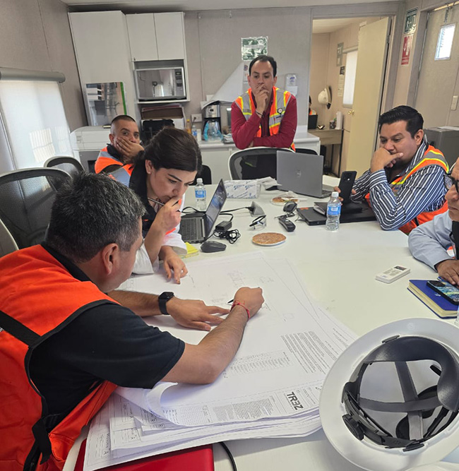 equipo técnico revisando planos y documentación ambiental para cumplimiento de normativas de emisiones atmosféricas en la industrial